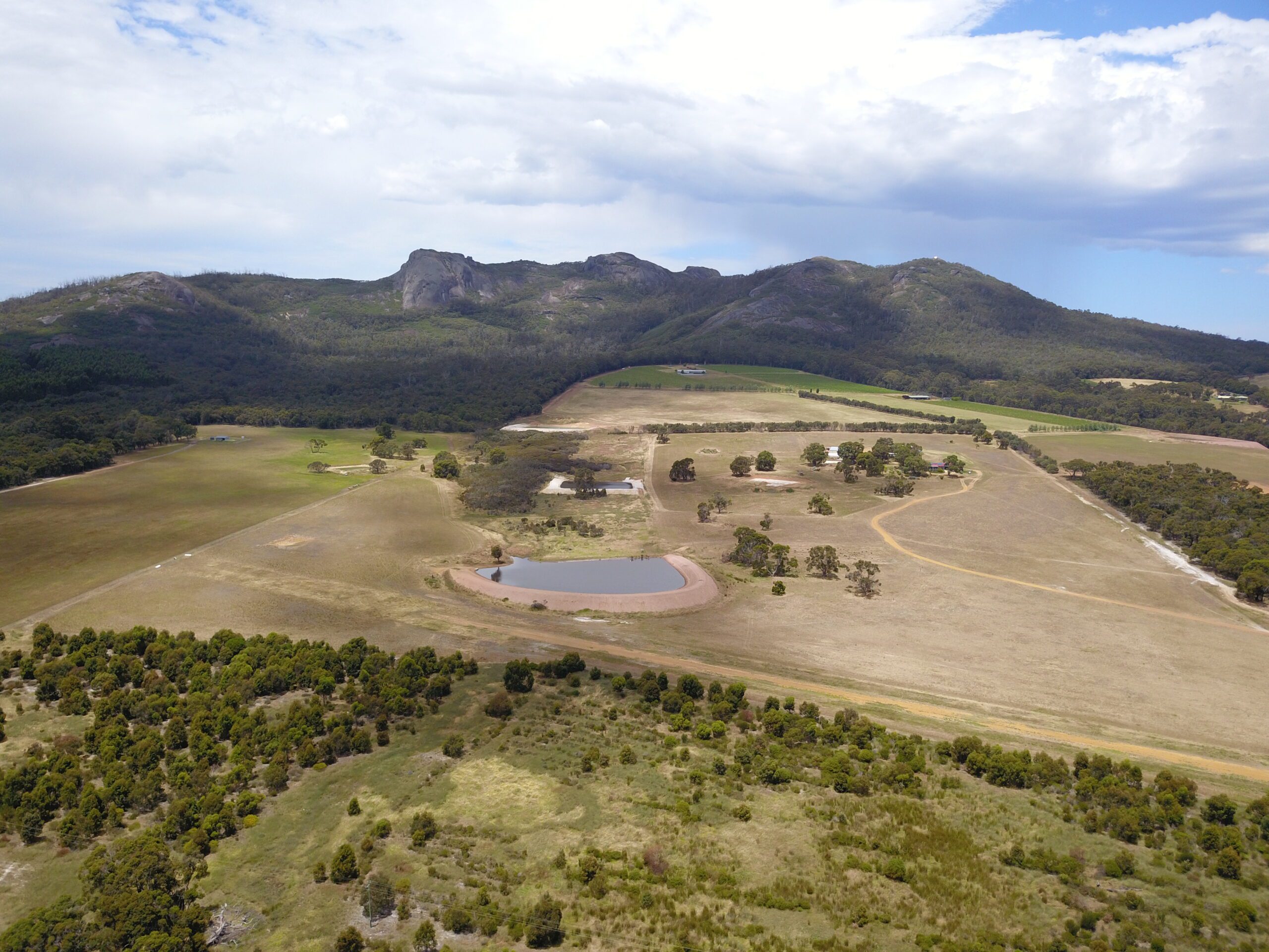 Drone photo of cleared paddock surrounded by remnant bush with ranges in the background